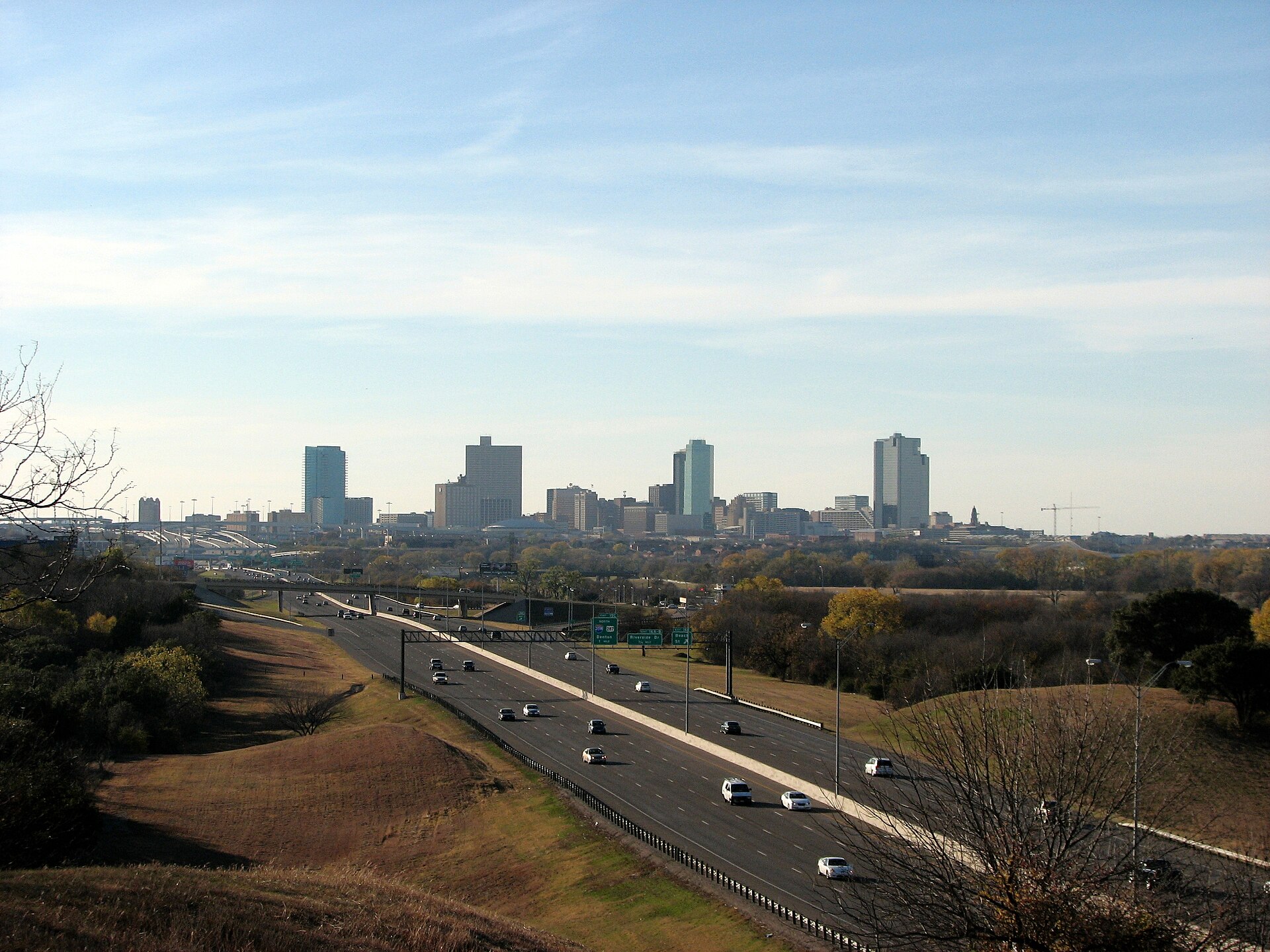 Fort Worth skyline beyond a highway and grassy hills